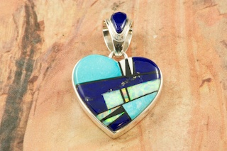 Genuine Blue Lapis, Turquoise and Black Jade inlaid between ribbons of Sterling Silver. Beautiful Fire and Ice Lab opal Accents. Stunning Pendant with precision inlay on the Bale and Pendant. Free 18" Sterling Silver Chain with Purchase of Pendant. Designed by Navajo Artist Calvin Begay. Signed by the artist.